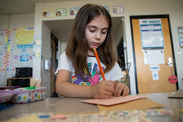 A little girl writes on an envelope