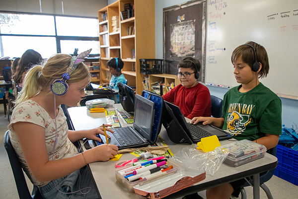 Students work on their Chromebooks with headphones on