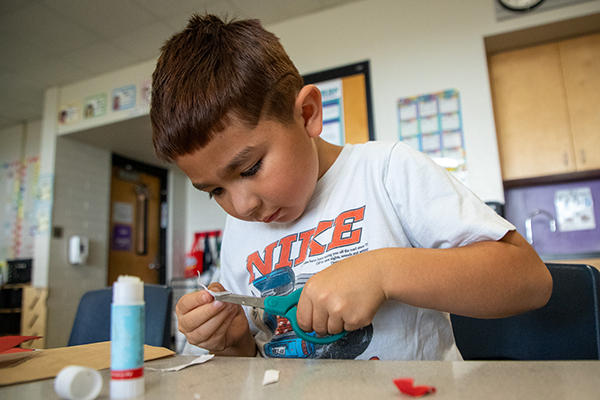 A boy cuts a piece of paper