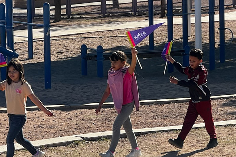 Students wave their purple Ruby Bridges pennants as they walk across the playground