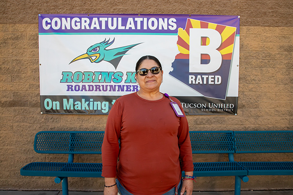 A woman in a red shirt stands in front of the Robins B Rated banner